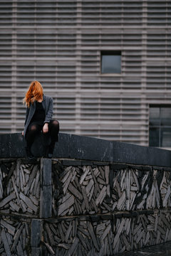 anonymous woman sitting in front of a functional architecture building