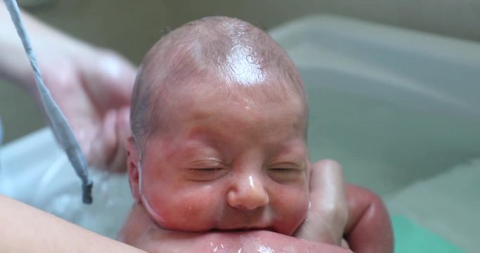 close-up of baby in small bathtub, Washing little newborn baby face and body