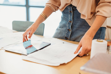 Young female fashion designer uses her tablet to make fashion sketches