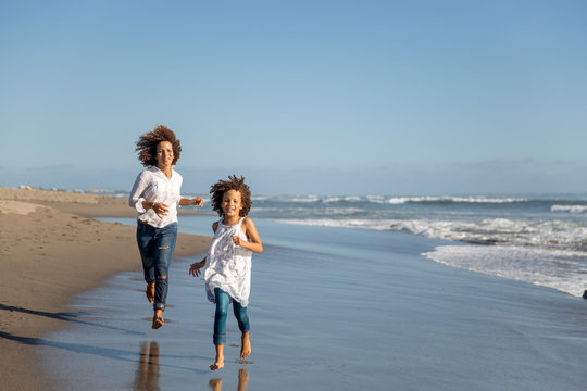 Mother and daughter running together at the beach