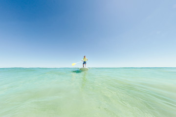 Riding a wave on a SUP at the beach in summer