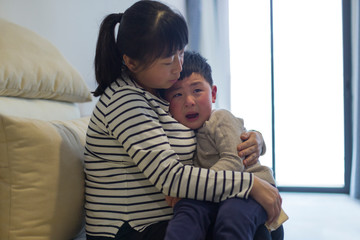 crying little boy in his mother's arm indoor