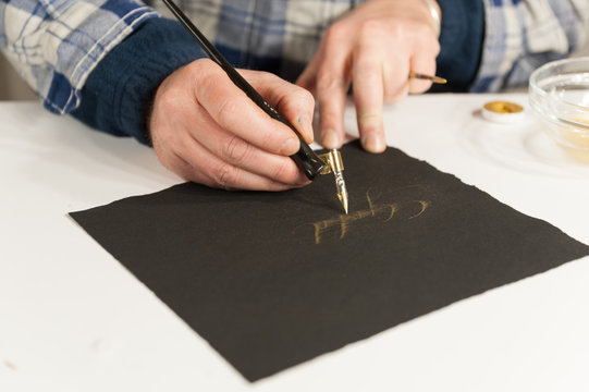 A Master Calligrapher writing elegant cursive lettering with a nib mounted on a oblique holder