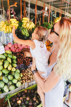 Little girl reaching for the bananas in the fruit store
