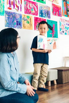 Preshool kid showing drawing to class