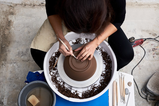 Anonymous artist scraping bottom of clay pot