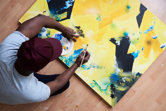 Artist painting abstract canvas with paintbrush.