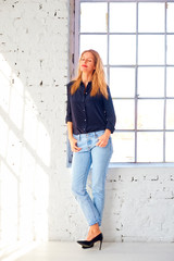 Attractive middle aged woman full length shot while standing by the window and daydreaming