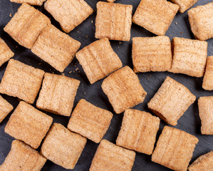 Crispy square wheat pillows on dark grey shale background. 