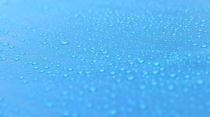 Fototapeta na wymiar Drops of water on a blue surface. Beautiful macro shot of water bubbles or dews.