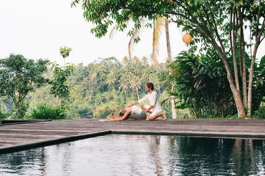 Male Yoga Teacher Assisting Female Practitioner in Outdoor Asan