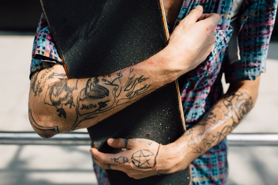 Close up of tattooed skater holding his skateboard