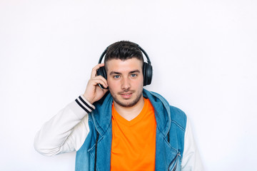 portrait of young man with headphones listening to music on a white background while looking camera