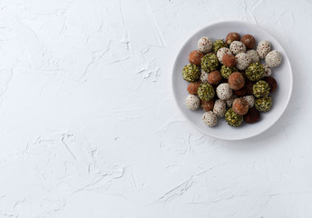 Organic energy bites with dates, pumpkin seeds, almond, walnut and sesame at the white background.