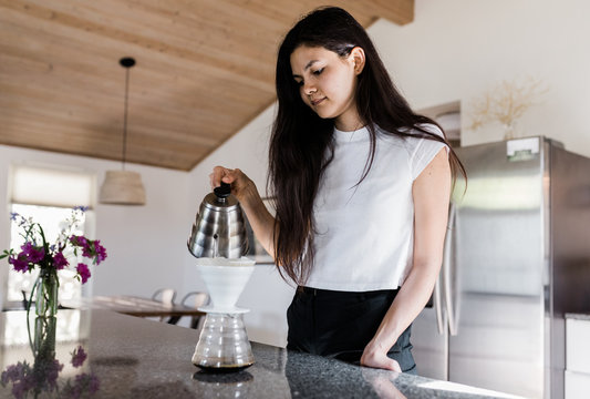 female pours water into coffee dripper