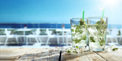Fresh cold mojito drink on desk and beach bar background. 
