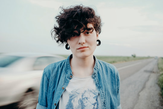 Portrait of a tomboy female model with ear plugs on the road