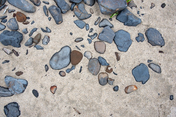 Fototapeta na wymiar Rocks and pebbles stuck in the sand at the beach