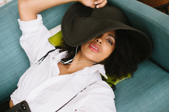 Young woman relaxing with headphones and floppy hat