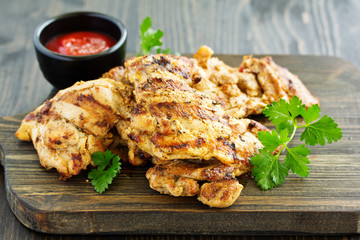 Grilled chicken fillet with tomato sauce and greens.