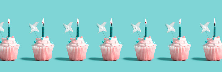 Tasty celebratory cupcakes with decorative lit candles