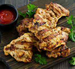 Grilled chicken fillet with tomato sauce and greens.