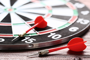 Obraz premium Dartboard with darts on brown wooden table