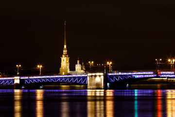 Long exposure photography of the Palace Bridge in Saint Petersburg at night with illuminated Peter and Paul Fortress in the background (St. Petersburg, Russia, Europe)