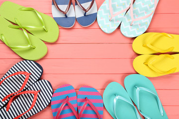 Pairs of colorful flip flops on wooden table