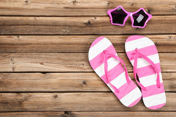 Pair of flip flops with sunglasses on brown wooden table