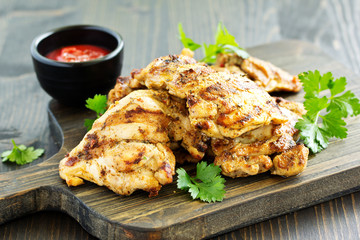 Grilled chicken fillet with tomato sauce and greens.
