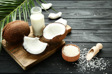 Coconut milk in bottle with flakes and palm leafs on wooden table