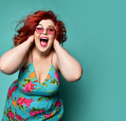 Happy plus-size lady fat woman holds her head with her arms and shouts or loud laughs having good...