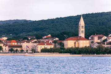 Supetar city in Brac island, Croatia. View from the sea. Picturesque scenic view on Supetar on Brac island, Croatia. Panoramic view on harbor of town Supetar from the side of sea. Brac, Croatia.