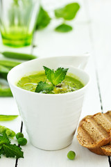 Green pea soup with croutons on wooden rustic background