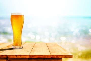 Cold beer in glass on wooden table and free space for your decoration. 