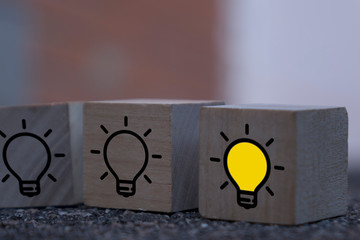 Creative idea, New idea, innovation and solution concept. wooden cubes with the yellow light bulb symbol on table, blue background, copy space
