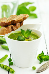 Green pea soup with croutons on wooden rustic background