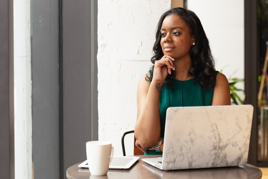 Businesswoman rests chin on hand in front of laptop