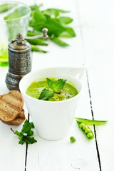 Green pea soup with croutons on wooden rustic background