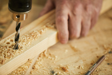 Extreme closeup of unrecognizable carpenter drilling wood while working in joinery, copy space