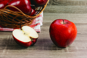 Ripe red apples full of vitamins on wooden table. Halved apple in half. Healthy fruit food for vegetarians and vegans. Apples in a wicker basket.