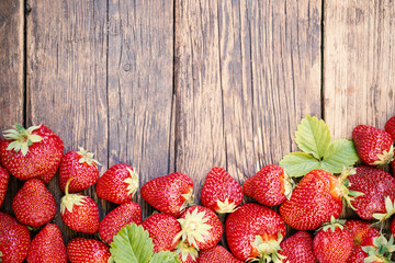Freshly picked juicy organic strawberries on rustic wooden table surface with copy space.
