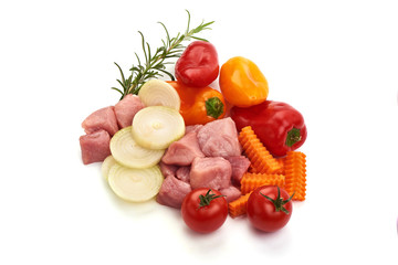 Raw cubed meat pieces, pork fillet with vegetables, ingredients for Hungarian goulash, top view, isolated on white background
