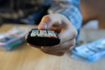 man's hand using the tv remote control from the bed
