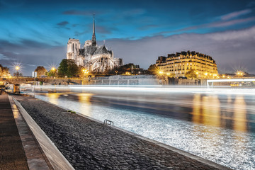 Notre Dame de Paris view from the Seine river with no people and riverboat light trails. One week...