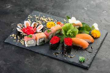 set roll decorated with flowers, japanese cuisine black stone background