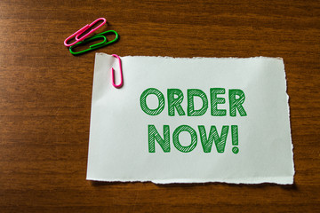 Word writing text Order Now. Business photo showcasing confirmed request by one party to another to buy sell Close up blank stationary paper hold three colored clips lying wooden table