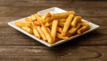 French fries fast food,french fries amount many pieces and mayonnaise, in dish square white all place on wooden table.