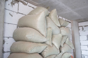 bags of construction material pile lie in a new building without finishing, gas block, concrete